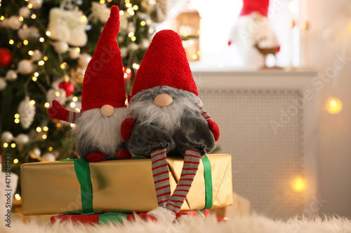 Cute Christmas gnomes and gift boxes on carpet in room photo