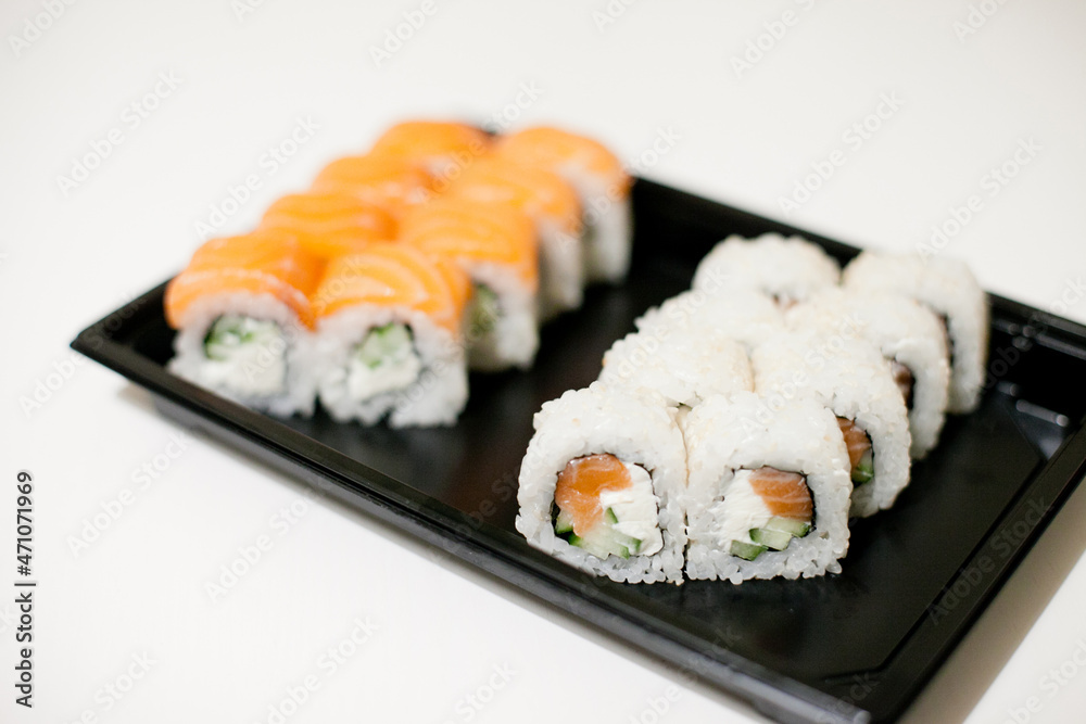 Sushi on a black plate takeout isolated. Japanese food delivery and takeaway. Sushi on a black plate takeout isolated. Japanese food delivery and takeaway.