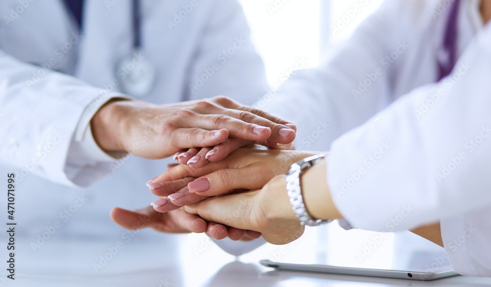 Team of doctors putting hands together, closeup Team of doctors putting hands together, closeup