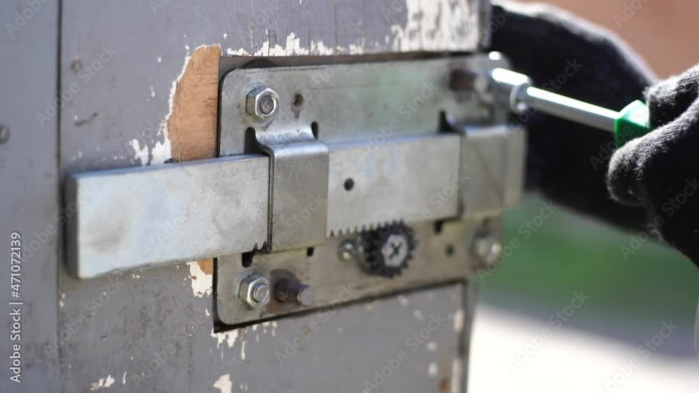 Repairing old door lock in rural barn or garage. Replacing broken part with new one Repairing old door lock in rural barn or garage. Replacing broken part with new one