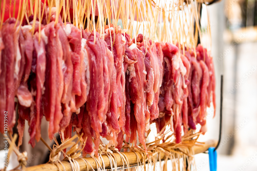 Sun-dried pork hung on a cart for frying for sale by the sea, Jomtien Beach, Chon Buri, Thailand