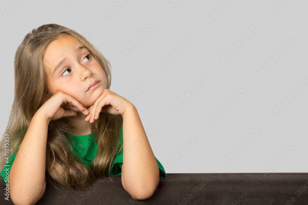 Little girl, child looking up with a pensive expression on her face