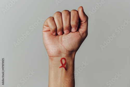 red ribbon for the fight against AIDS in his wrist photo