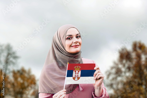 Muslim woman in hijab holds flag of Serbia 