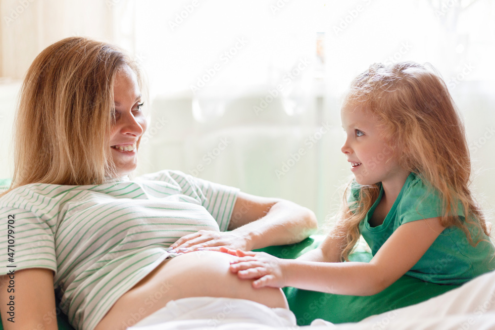 Happy daughter gently touches hug mom's pregnant belly. Portrait of daughter kid child and smiling pregnant mother. A parent's tenderness and love in family Happy daughter gently touches hug mom's pregnant belly. Portrait of daughter kid child and smiling pregnant mother. A parent's tenderness and love in family