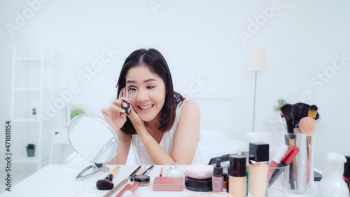Fototapeta Naklejka Na Ścianę i Meble -  Beauty blogger present beauty cosmetics sitting in front camera for recording video. Happy beautiful young Asian woman use cosmetics review make up tutorial broadcast live video to social network.