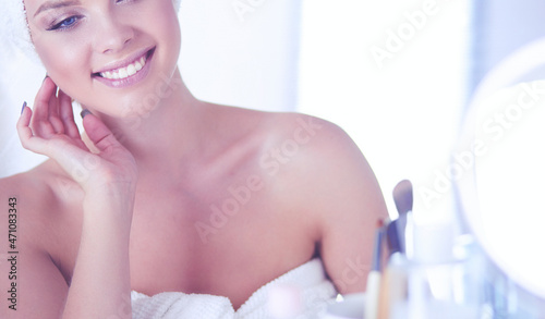 Young woman in bathrobe looking in bathroom mirror