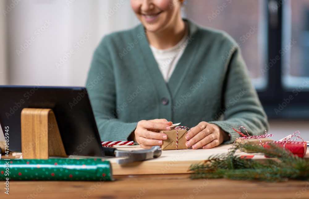 winter holidays and hobby concept - close up of happy smiling woman with tablet pc computer packing christmas gift or making advent calendar at home winter holidays and hobby concept - close up of happy smiling woman with tablet pc computer packing christmas gift or making advent calendar at home