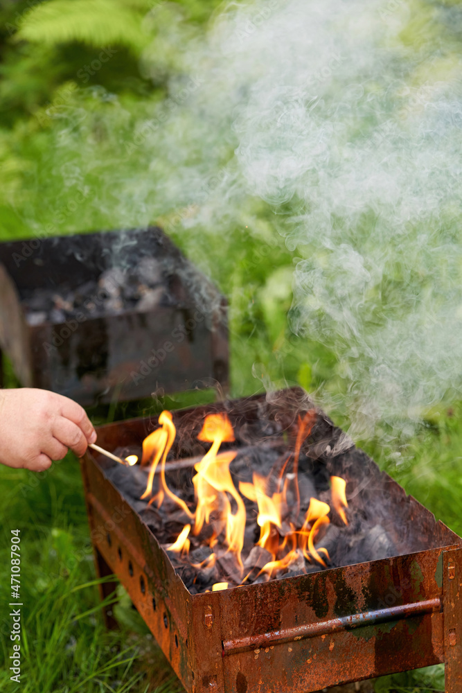 Firing up an old rusty metal barbecue grill, smoke and fire Firing up an old rusty metal barbecue grill, smoke and fire