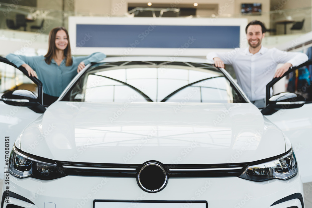 Closeup choosing new car before buying it. Heterosexual caucasian young family purchasing new auto at dealer car shop, doing test-drive Closeup choosing new car before buying it. Heterosexual caucasian young family purchasing new auto at dealer car shop, doing test-drive