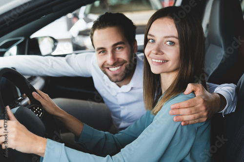 Cheerful smiling caucasian young family couple embracing hugging during test-drive of their new car before buying purchasing auto at dealer shop © InsideCreativeHouse