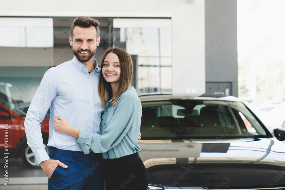 Happy young caucasian heterosexual couple family husband and wife hugging embracing after buying new car auto at automobile dealer shop store. Happy young caucasian heterosexual couple family husband and wife hugging embracing after buying new car auto at automobile dealer shop store.