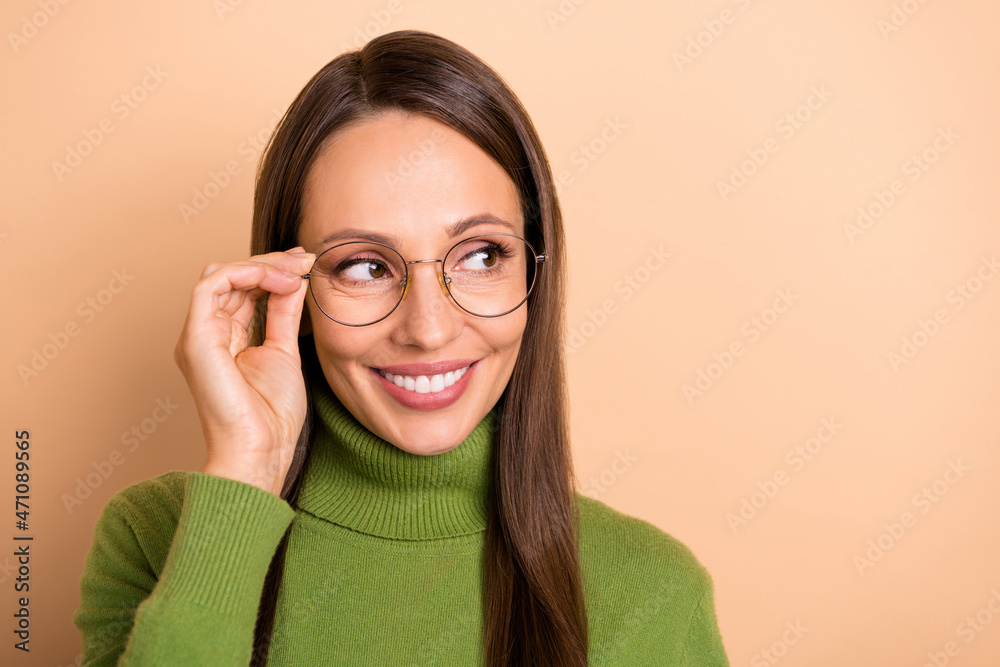 Photo of young curious lady look empty space wear eyewear green pullover isolated on beige color background Photo of young curious lady look empty space wear eyewear green pullover isolated on beige color background