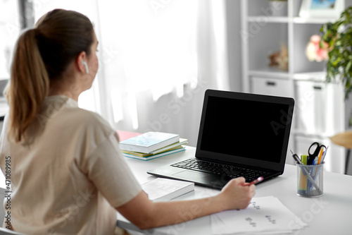 distant education  remote job and people concept - female math teacher with laptop computer and earphones working at home office