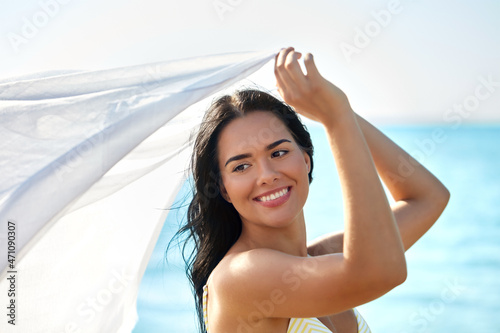 people, summer and swimwear concept - happy smiling young woman in bikini swimsuit with cover-up on beach
