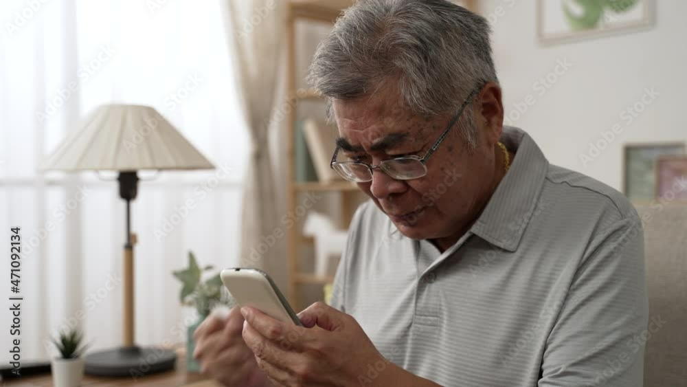 Emotional old asian man in glasses looking at cellphone screen celebrate winning mobile game or getting price in online lottery. elder male read message with unbelievable pleasant news on smartphone Emotional old asian man in glasses looking at cellphone screen celebrate winning mobile game or getting price in online lottery. elder male read message with unbelievable pleasant news on smartphone