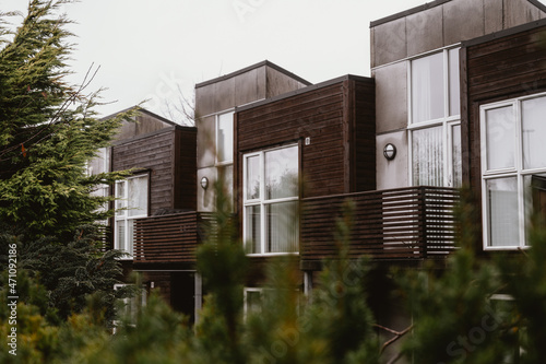 Modern exterior of residential building. Wooden facade in scandinavian style. Green trees. Urban architecture in Norway.