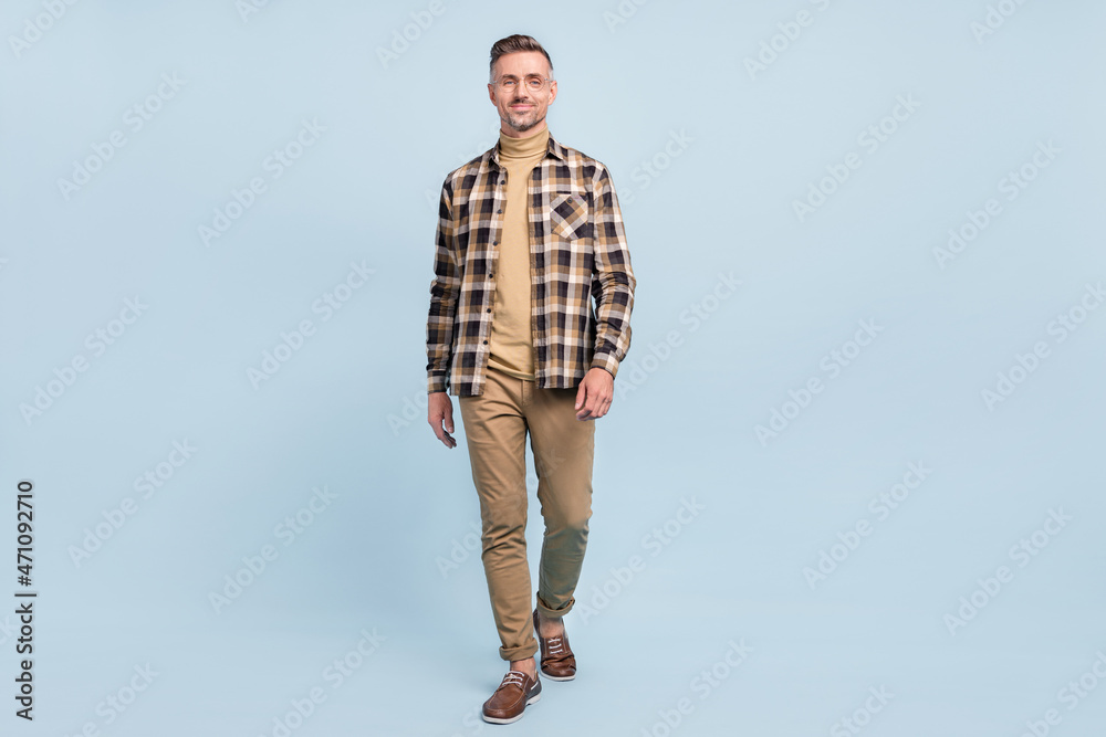 Full length photo of mature man good mood walk wear casual clothes isolated over grey color background Full length photo of mature man good mood walk wear casual clothes isolated over grey color background