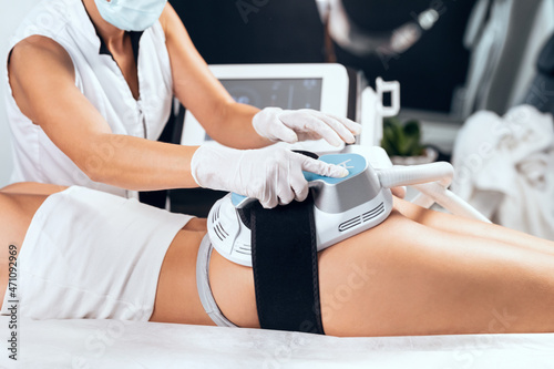 Woman lying receiving epilation laser treatment and anticellulite massage on buttock on the spa center. photo