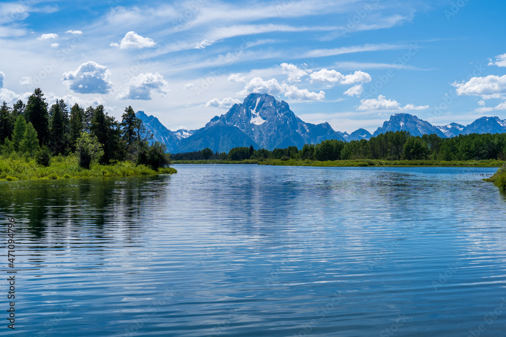 The Snake River with the Grand Teton mountain range reflecting in the background on a sunny day near Jackson Hole, Wyoming