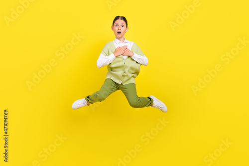 Full length body size view of attractive funny impressed girl jumping touching heart isolated on bright yellow color background