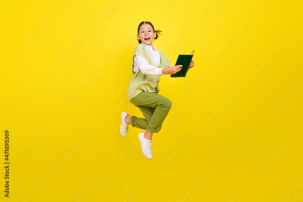 Full length body size view of attractive cheery trendy smart girl jumping reading book isolated over bright yellow color background