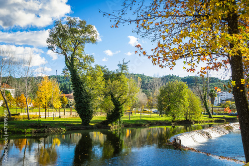 Beautiful park with river and stone bridge in the village of Serta - Portugal. Autumn folliage trees reflecting on the water. Roman ancient bridge over the river