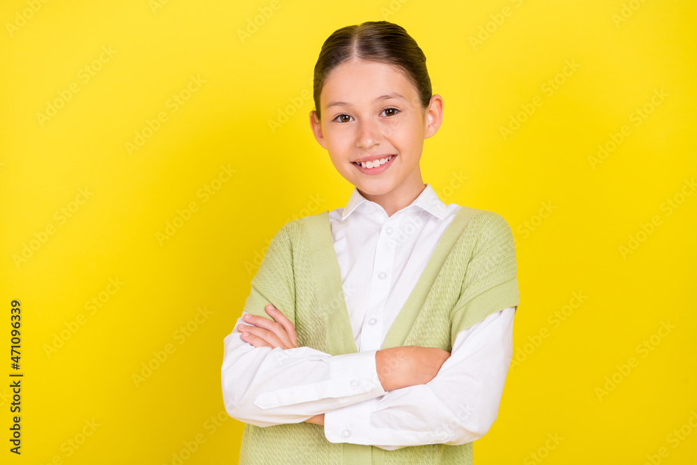 Portrait of attractive sweet gentle cheerful preteen girl wearing vest folded arms isolated over bright yellow color background Portrait of attractive sweet gentle cheerful preteen girl wearing vest folded arms isolated over bright yellow color background
