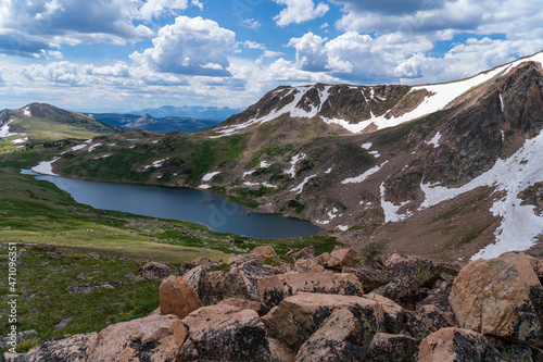An alpine lake off the Beartooth Highway in the Absaroka Mountains of Wyoming and Montana - snow capped mountains, green grass, blue lake