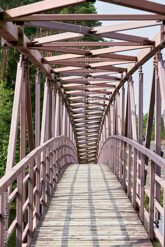 An arched pedestrian bridge over the river with a wooden deck