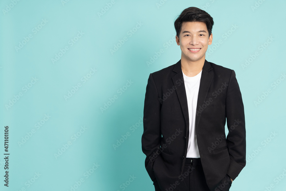 Smiling young Asian businessman in black suit isolated on green background Smiling young Asian businessman in black suit isolated on green background