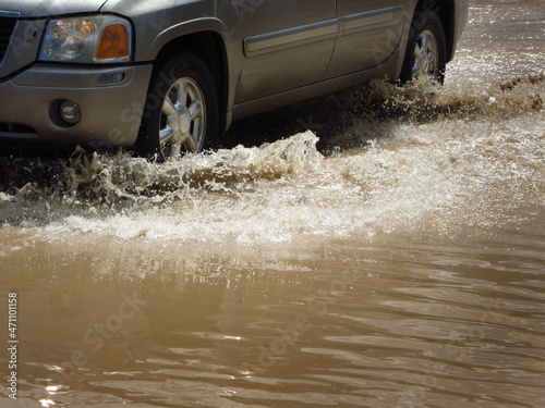 Car Driving Through Flooded Street Tires Splashing Water
