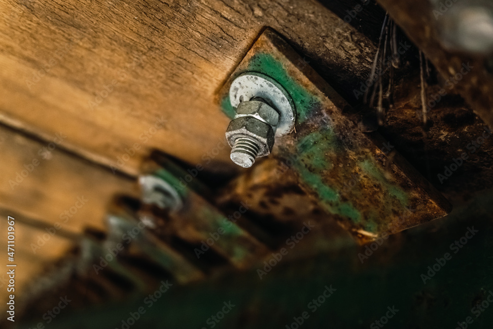 Nut with screw holds the old planks of a wooden bridge, detail.