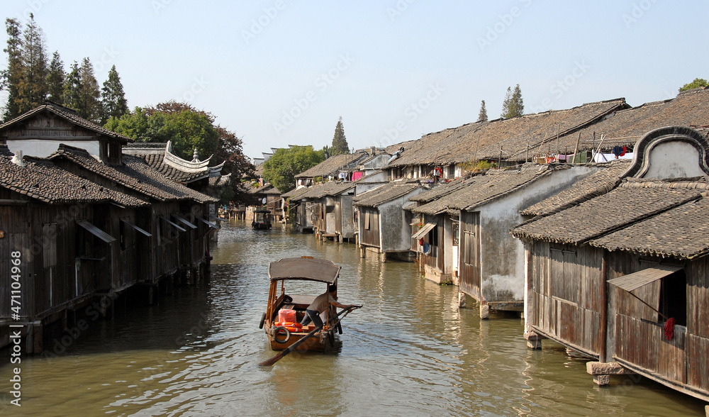 Wuzhen Water Town, Zhejiang Province, China. A small boat carrying tourists explores the old town and canals of Wuzhen. Unrecognizable people.