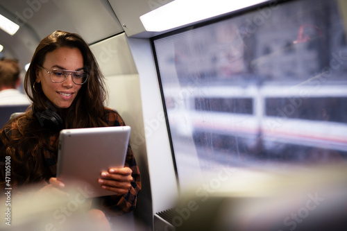 Young beautiful girl travelling by train. Smiling woman using digital tablet