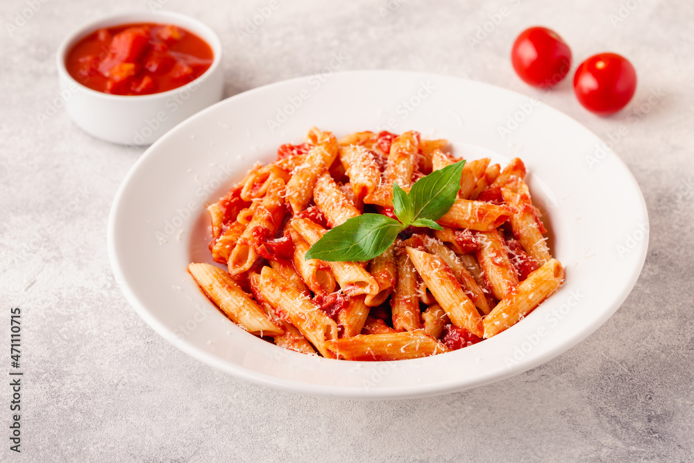Classic italian pasta penne alla arrabiata with fresh basil on a light background Classic italian pasta penne alla arrabiata with fresh basil on a light background