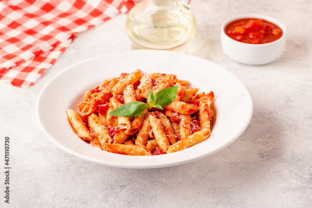 Classic italian pasta penne alla arrabiata with fresh basil on a light background Classic italian pasta penne alla arrabiata with fresh basil on a light background