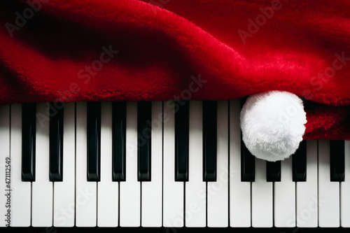 Christmas music background. Santa Claus hat and piano keys, keyboard. Playful red white black Christmas.