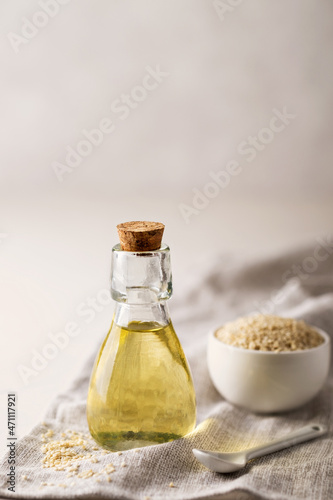 Sesame oil in a glass bottle and sesame seeds on the table. Copy Space