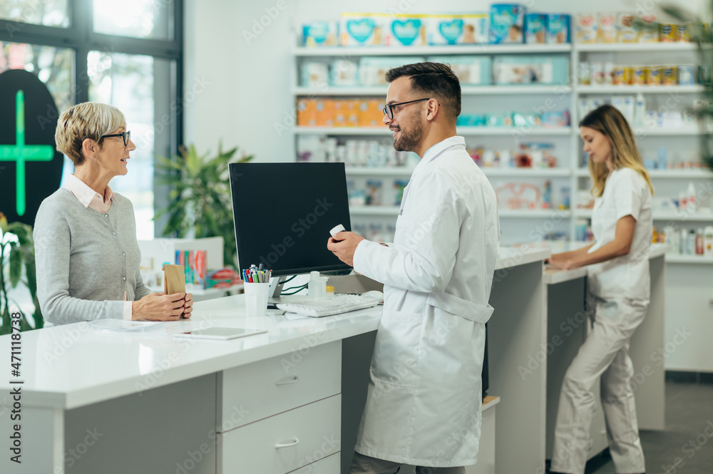 Young male pharmacist giving prescription medications to senior female customer in a pharmacy Young male pharmacist giving prescription medications to senior female customer in a pharmacy