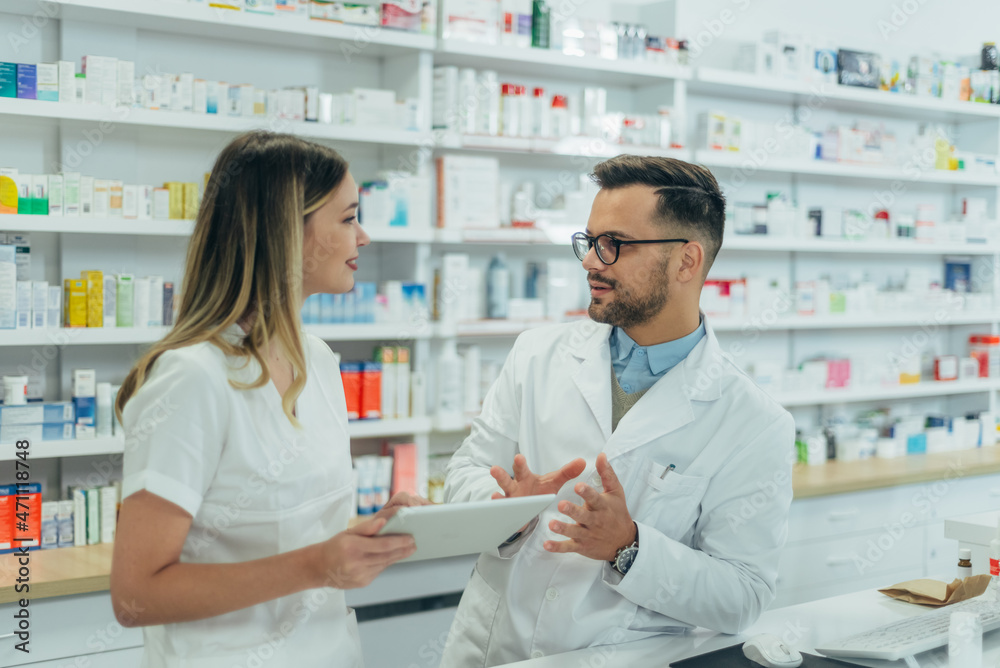 Male pharmacist working with young female colleague in a pharmacy