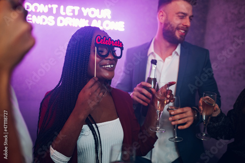 Happy group of friends dancing on a party in a club while drinking champagne