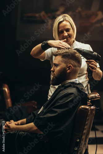 Young bearded man getting haircut by hairdresser