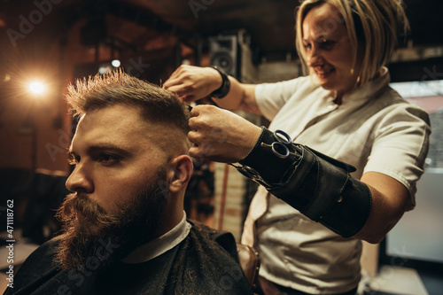 Young bearded man getting haircut by hairdresser