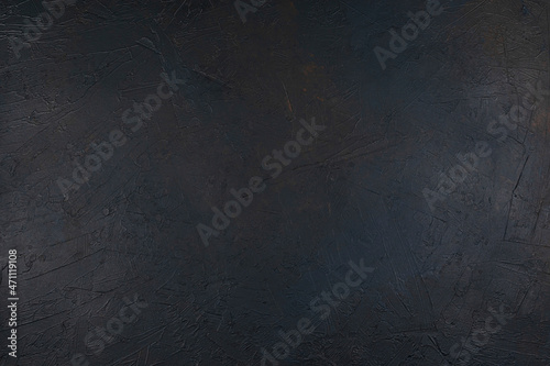 Dark textured concrete background with blue and brown streaks. Rough, rough texture. Top view