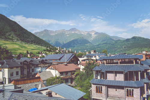 Beautiful highland townlet Mestia in the Svaneti region, Georgia, Asia. Cityscape view of traditional rural houses with green hills, famous towers and mountains in the background