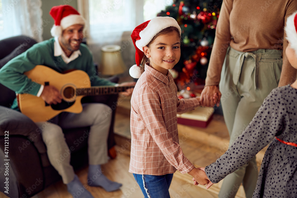 Fototapeta premium Happy girl has fun while celebrating Christmas and dancing with her family.