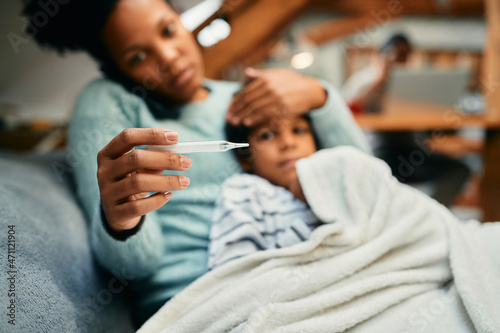 Close-up of black mother measuring sick son's temperature. photo