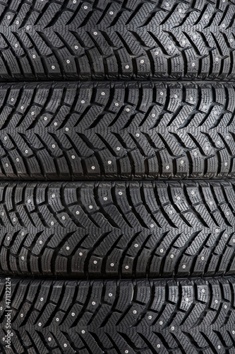 New winter car tires with spikes close-up vertically. Texture, background