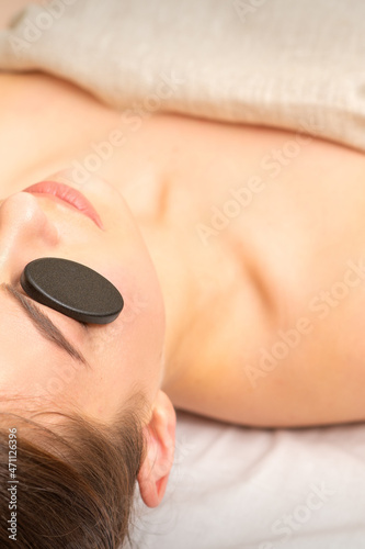 Massage with stones on the eyes of young woman getting a treatment in a beauty spa